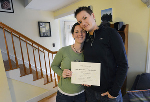 Alissa Poisson and Maggie Oechslie of South Portland hold a certificate that Maggie’s father made and presented to the couple at their public commitment ceremony last year. Now, with Tuesday’s approval of the same-sex marriage initiative, they plan to be first in line to get a legal Maine marriage license. They are expecting their first child in May.