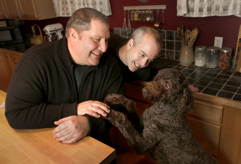 David Jacobs, left, and Paul Jacobs play with their dog Godiva in their home in South Portland on Friday. The couple of 22 years recently got engaged and plan to get married in July.