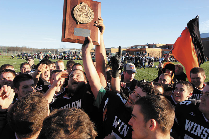 WESTERN C CHAMPS: The Winslow High School Black Raiders celebrate their Western C title after defeating Dirigo High School 17-6 on Saturday in Winslow. Holding the trophy is Brock Deschaine, center, and Jon Farrell, right.