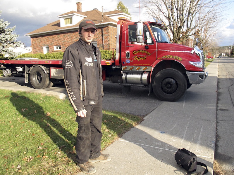 In this Nov. 13, 2012 photo, Nicholas Dostie stands in front of his tow-truck in Magog, Quebec, that he said he used to tow a van in which about a dozen men, women and children entered Canada illegally from the United States and applied for political asylum. Canadian immigration officials on Wednesday, Dec. 5, 2012 said a Romanian smuggling ring has been bringing Gypsies into the U.S. through Mexico in order for them to eventually gain asylum in Canada. (AP Photo/Wilson Ring)