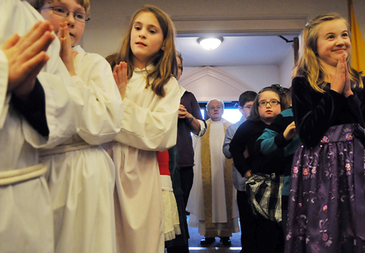 Children line up to lead Fr. George Hickey, center, into the Christmas Eve Mass at Sacred Heart Catholic Church in Hallowell on Monday.
