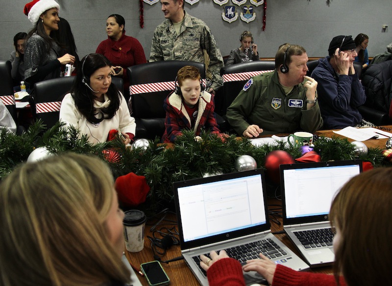 U.S. Air Force Brig. Gen. Richard Scobie, right, flanked by his son Andrew, and wife Janis, all taking phone calls from children asking where Santa is and when he will deliver presents to their house, during the annual NORAD Tracks Santa Operation, at the North American Aerospace Defense Command, or NORAD, at Peterson Air Force Base, in Colorado Springs, Colo., Monday Dec. 24, 2012. Over a thousand volunteers at NORAD handle more than 100,000 thousand phone calls from children around the world every Christmas Eve, with NORAD continually projecting Santa's supposed progress delivering presents. (AP Photo/Brennan Linsley)