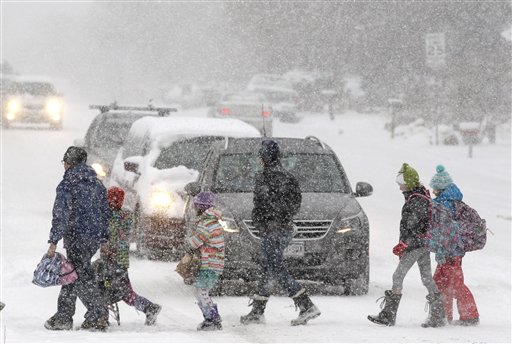 Elementary school students escorted by parents cross a snowy street en route to school as a blizzard dropped snow over Boulder, Colo., on Wednesday. The storm is on track to hit the central plains and Midwest on Thursday.