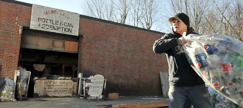 Steve Hodgkins tosses bottles into a truck Monday at his Winthrop redemption center, M.T. Bottle Co. The firm is moving to a new location.
