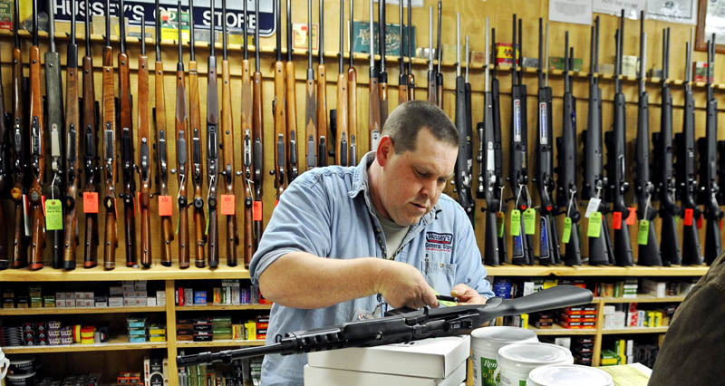 Jasen Pelletier prepares a Ruger Mini-14 rifle he sold in the gun department at Hussey's General Store on Saturday, in Windsor. Gun sales are strong, according to store staff.