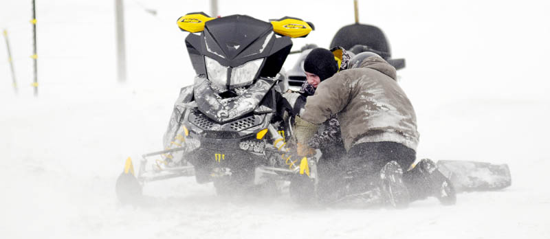 Alex, left, and his father, Mike McPherson, inspect the engine of a snowmobile Sunday, in Farmingdale. The men were taking a run together to celebrate Alex's 17th birthday when his sled developed some engine problems. The snow machine was driven to a cousin's barn to inspect the plugs.
