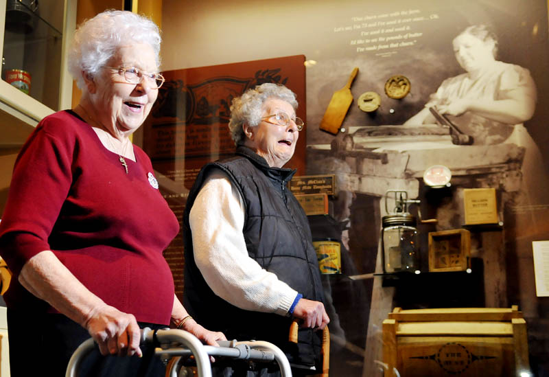 Jeanne Chamberland, left, 88, of St. Agatha and her sister, Lillian Bussier, 84, of Lewiston, laugh after viewing a photo Friday of their mother, Emma Gagnon, pouring buttermilk. The photo, captured by Farm Security Administration photographer John Collier Jr. while documenting the Gagnon family's potato farm in Frenchville, is on display at the Maine State Museum in Augusta. Gagnon, a mother of 11 children, passed away from tetanus at the age of 42, two years after the photo was created. It was the first time Chamberland saw the photo.