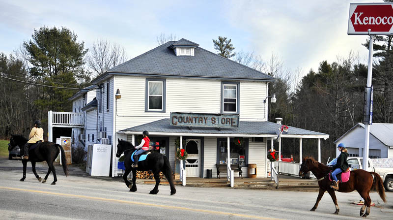 Jana Christman, left, leads her friend, Emily Boedeker, 11, center, and daughter, Emma Christman, 12, past the Litchfield Country Store on horseback Sunday. The trio were riding along the edge of the road with their steeds before taking to trails through the woods to loop back to their Litchfield homes.