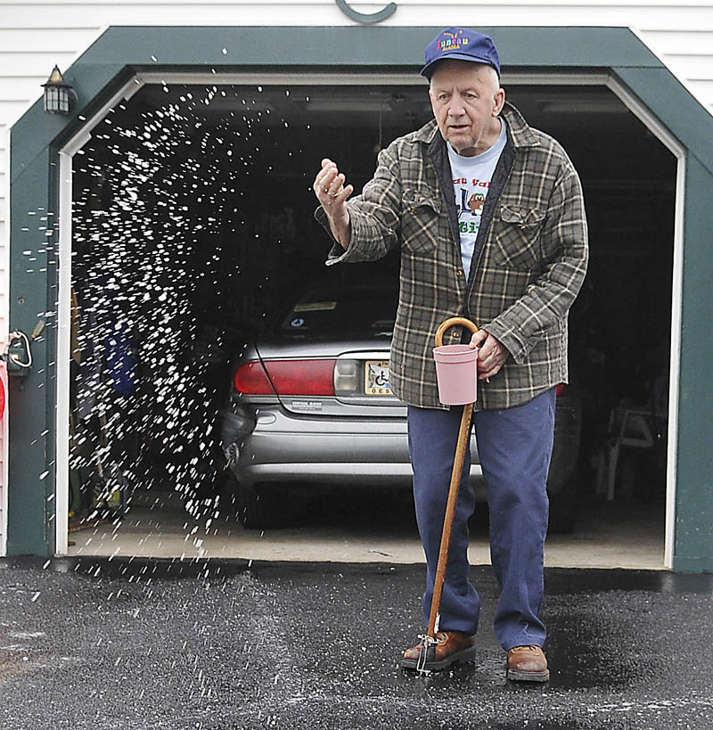 Hiram Cochran spreads salt Monday on the driveway of his Augusta home. Slick conditions greeted drivers across the state after rain and snow fell overnight, with icy mist persisting throughout the day. Cochran said he likes to keep the entrance to his home free of ice to accommodate getting the mail.