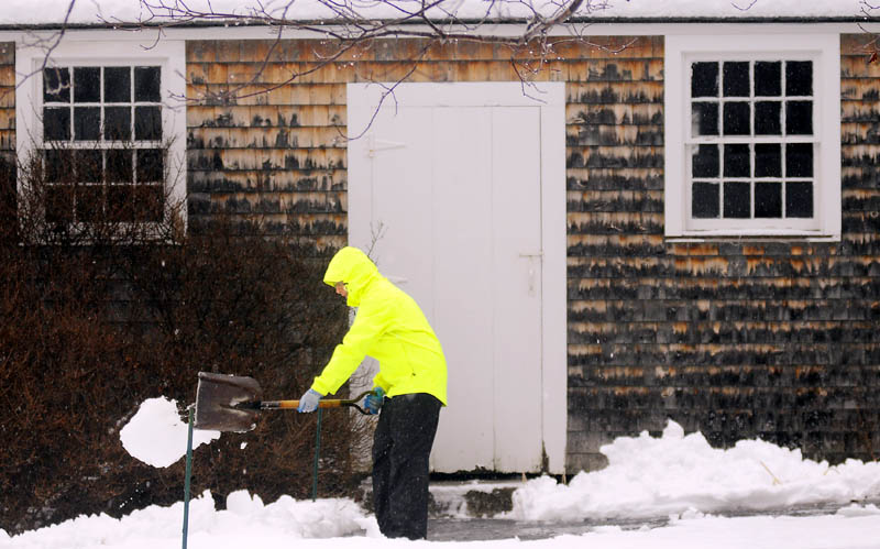 Nancy Russell, of Readfield, moves slush away from the walkway of her shed Tuesday, as rain descends upon the fresh coat of snow. "It's a lovely day to shovel," Russell remarked. "It will all turn to ice if I don't shovel it now."