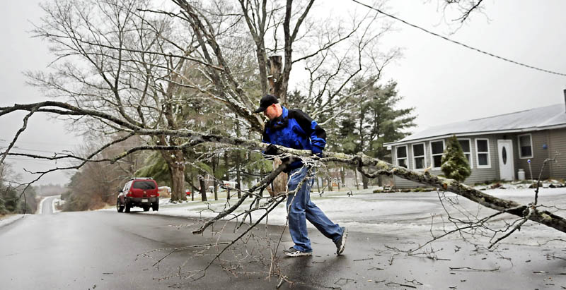 John Smith moves a limb Monday from the lawn of his mother-in-law's Augusta home. Smith said the late fall weather is "not bad this year."