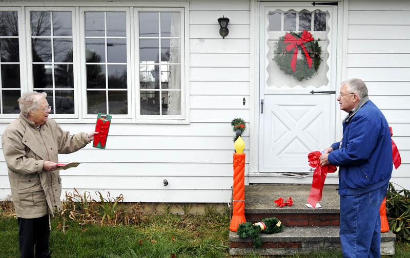 Lora Briggs, 86, directs her son-in-law, Howard Cooke, how to display ribbons recently at her Monmouth home. Briggs said that Cooke mows, trims, and hangs the holiday ornaments with only limited supervision. "He's really improved the last 10 years," she joked.