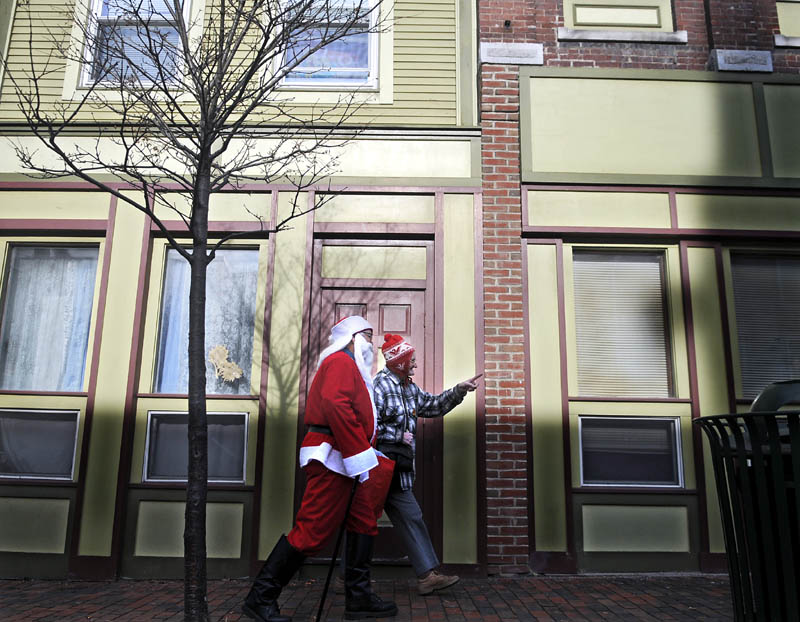Santa Claus and Elizabeth Conary stroll down Water Street in Gardiner on Thursday. Stores were doing brisk business at midday in the middle of the holiday shopping season, beneath clear-blue skies. Kringle and Conary stopped and chatted with several shoppers and merchants during their constitutional through town.