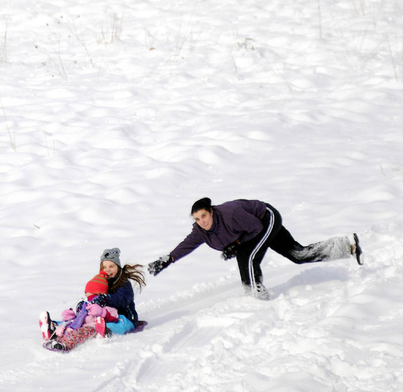 Jennifer Fielding launches her daughter, Abbie, 9, rear, and Lia Umland, 5, in a sled Sunday, down a hill at the Oaklands Farm in Gardiner. Another six inches of snow fell between Saturday and Sunday, creating perfect conditions for winter expeditions. The Fieldings, of Gardiner, were accompanied by their son, Connor, 7, on the downhill adventure.