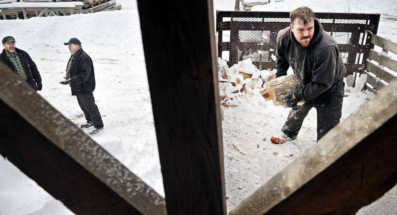 Mike Baker, left, confers with Paul Peaslee Sr., on Sunday as his son, Paul Peaslee Jr., unloads several cords of firewood at Baker's Smelt Camps in Pittston. The elm and ash keep the shacks that sit on the frozen river warm for winter anglers, Paul Peaslee Jr. said. Baker said that camps, which burn about 25 cords a winter, should be opening next week.