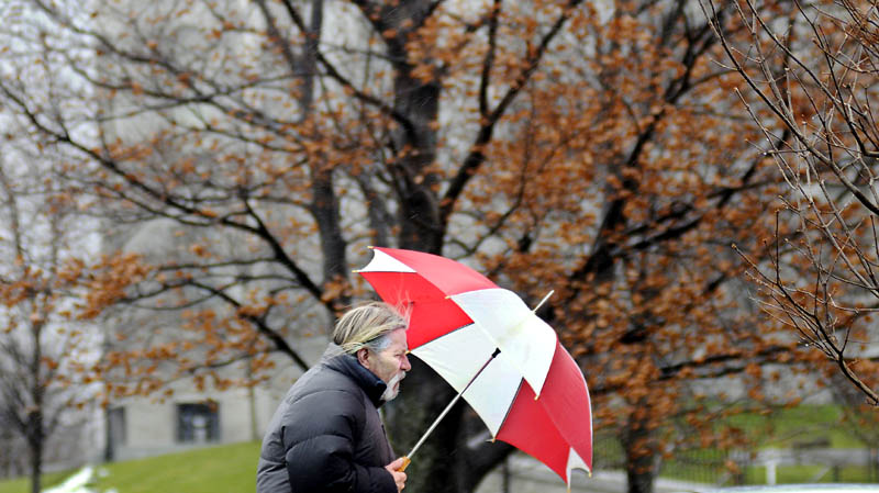 Dana Philippi walks into the rain Friday in Augusta. Philippi was returning to his office in a heavy rain.