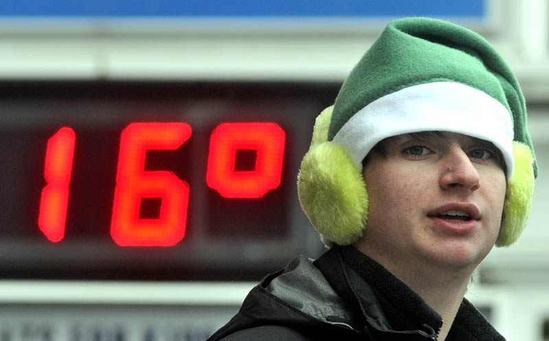 Kegan Blood, 16, of New Sharon, doubles up with the hat and earmuff combo as 16 degrees flashes on the Franklin Savings Bank sign, while tending the hot chocolate table at Franklin Savings Bank on Main Street, during the Chester Greenwood Day parade in downtown Farmington Saturday.