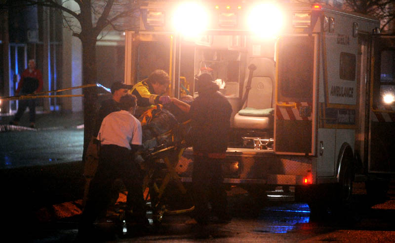 Staff photo by Michael G. Seamans The victim of a shooting is loaded into an ambulance on The Concourse in Waterville late Tuesday night.