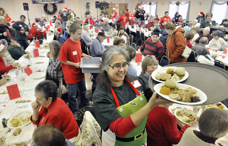 Stacey Hachey, center, delivers a tray of turkey dinners to tables at the Central Maine Family Christmas Dinner at the Elks lodge in Waterville on Tuesday. More than 500 dinners had been served by noon.