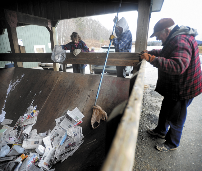 Reggie Lane, center, an employee at the Wilton Transfer Station, fishes a plastic bag out of the single-stream dumpster as Lawrence Farrington, right, and his wife, Marcella, left, throw away recylable materials on Wednesday. Although the new recycling method is single-stream, some materials need to be excluded, such as plastic shopping bags.