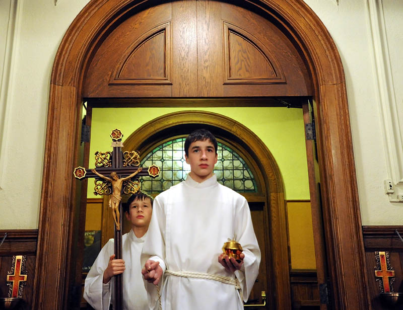 William Couture, 15, front, and his brother, Edmund, 11, both altar servers, prepare for the beginning Midnight Mass at Sacred Heart Catholic Church on Pleasant Street in Waterville on Tuesday.
