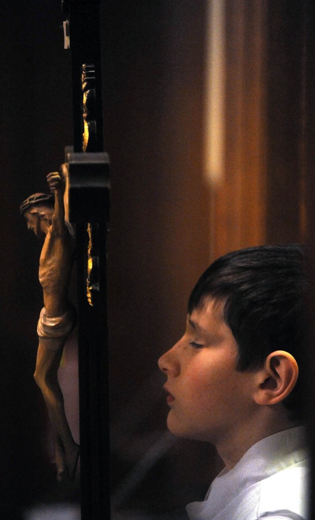 Edmund Couture,11, an altar server, struggles to keep his eyes open before the start of Midnight Mass at Sacred Heart Catholic Church on Pleasant Street in Waterville on Tuesday.