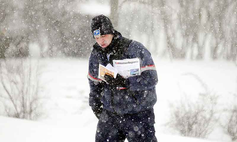 Mail carrier Devin Saban delivers mail Thursday in Hallowell, just as the storm begins to move through the area. Several inches are forecast and all state offices are closed.
