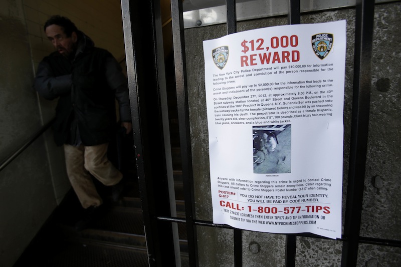 A reward poster is displayed on the entrance to the 40th St-Lowry St Station, where a man was killed after being pushed onto the subway tracks, in the Queens section of New York, Friday, Dec. 28, 2012. Police are searching for a woman suspected of pushing the man and released surveillance video Friday of her running away from the station. (AP Photo/Seth Wenig)
