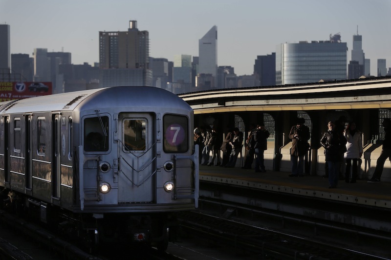 Commuters wait on the platform as a train passes through the 40th St-Lowry St Station, where a man was killed after being pushed onto the subway tracks, in the Queens section of New York, Friday, Dec. 28, 2012. Police are searching for a woman suspected of pushing the man and released surveillance video Friday of her running away from the station. (AP Photo/Seth Wenig)