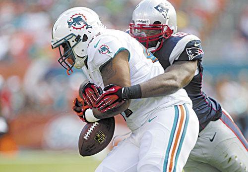 NICE DEFENSE: Miami fullback Jorvorskie Lane fumbles the ball as he is tackled by New England linebacker Jerod Mayo during the first half Sunday in Miami. The Dolphins recovered the ball.