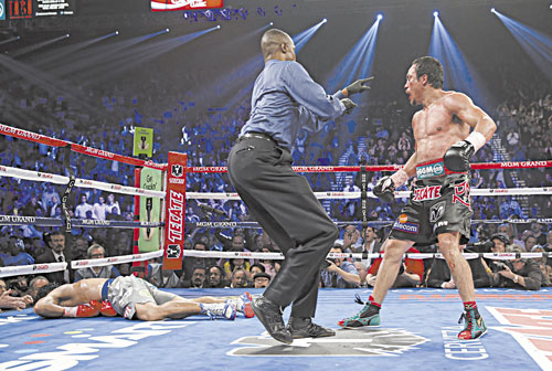 IT’S OVER: Referee Kenny Bayless, center, sends Juan Manuel Marquez, right, to his corner after Marquez knocked out Manny Pacquiao, left, in the sixth round of their WBO world welterweight fight Saturday in Las Vegas. Marquez won the fight by a knockout.