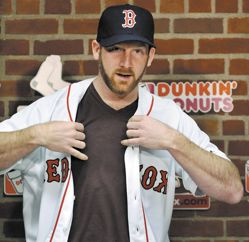 A NICE FIT: New Boston Red Sox pitcher Ryan Dempster puts on his jersey during a press conference Wednesday in Boston. Dempster signed a two-year, $26.5 million contract with the Red Sox.