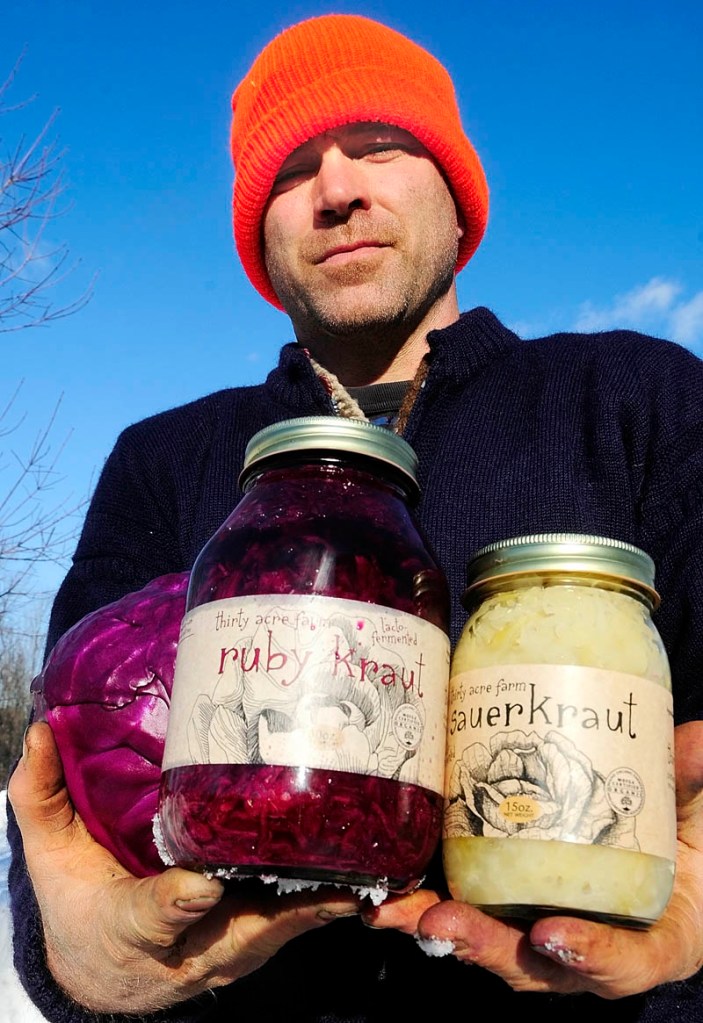 Simon Frost holds up some of the sauerkraut he made at his Thirty-Acre Farm in Whitefield, on Monday.