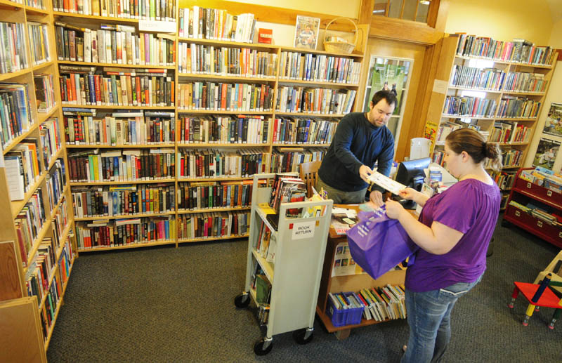 Belgrade library assistant Jared Bond, left, checks out books for Gina Davis on Thursday at the Belgrade Library, located in the Belgrade Community Center for All Seasons. The boxes at right are packed up for the upcoming move to the library's new Depot Road location, which will open Dec. 18.