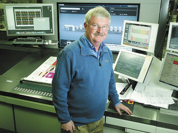 Rick Tardiff, president of J.S. McCarthy Printers, stands beside the control station of one of the company's Komori printing presses on Dec. 4 in Augusta.