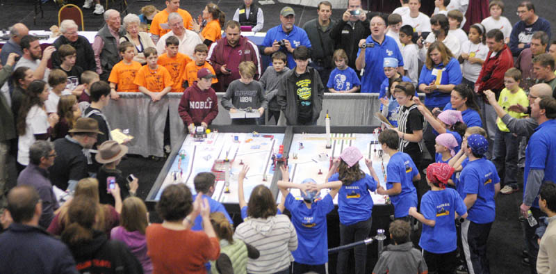 Team members and spectators gather a round a table as a pair of teams compete at the 13th annual Maine First LEGO League Championship on Saturday, at the Augusta Civic Center.