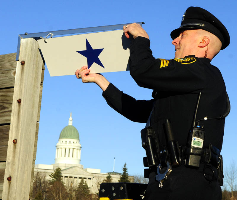 Augusta police Sgt. Christian Behr hangs a blue star, in honor of patrolman Eric Dos Santos, who is serving in Afghanistan on his second deployment with the Maine Army National Guard, on Saturday, at Augusta Police headquarters.