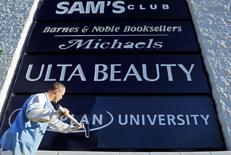 Tim Wing, of Northeast Painting and Coating, puts another coat of blue onto a Marketplace at Augusta sign on Monday afternoon in Augusta. The letters are inset, so he was able to just go over them with a roller. He said that the signs would be topped off with a new sign for the Walmart Supercenter.