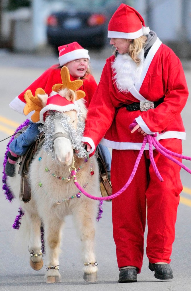 Madyson Beaulieu, left, 4, rides on Flash the pony led by Michele Gatie, 18, both of Smithfield, during the 6th annual Hemphill's Christmas parade on Sunday, on Oak Grove Road in North Vassalboro.