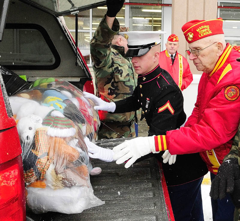 Marine Pfc. Evan Goodwin, left, and Marine Corps League member Dana Walls, of West Gardiner, load a bag of toys donated for the Toys for Tots campaign into a vehicle in Augusta on Monday. Goodwin and another Marine were picking up the toys donated by the Western Maine Young Marines and the Marine Corps League Detachment 599.