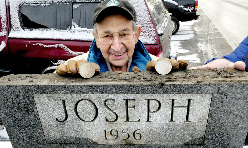 Bill Joseph, 94, stands behind the corner stone of a former beer store he once owned in Fairfield. The stone was removed from a building that will be demolished beside the Gerald Hotel to make room for parking. Under the stone were two silver dollars Joseph is holding.