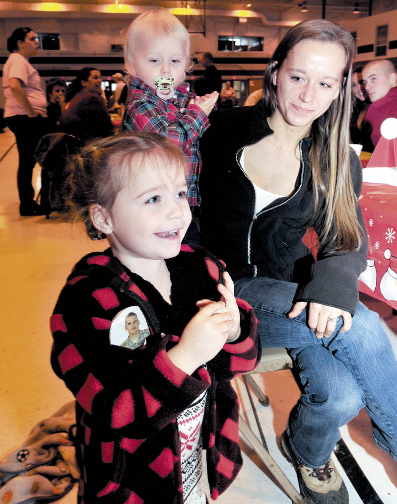 Cheyenne Allen, of Strong, wearing a button with a photo of her father, Sheldon Allen, reacts with joy as Santa enters the armory in Waterville on Sunday. Her mother, Emma, and brother, Elias, sit behind her during a family Christmas party for families of soldiers in the 488th Military Police Company, serving in Afghanistan.