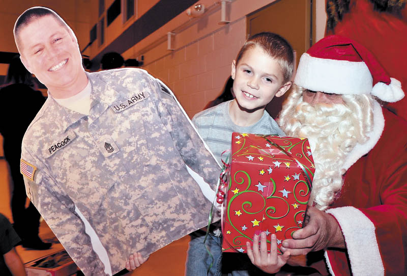 Colby Peacock had his hands full with a present from Santa and a large photo he brought of his father, 1st Sgt. Michael Peacock, during a Christmas party for families of soldiers in 488th Military Police Company, serving in Afghanistan, at the armory in Waterville on Sunday.