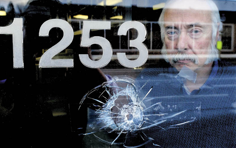 Jeff Rose, business manager for the International Brotherhood of Electrical Workers Local 1253, on Monday is seen behind one of seven bullet holes that shattered windows and walls at the office on Main Street in Fairfield. Someone shot at the building last Thursday evening while the office was occupied. There were no injuries.