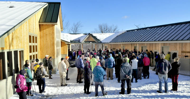 People assemble between the lodge, at left, and the bunk house to listen to speakers during the grand opening of the fourth hut in the Maine Huts and Trails system in Carrabassett Valley on Wednesday.