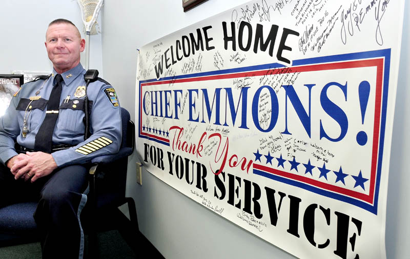 Skowhegan Police Chief Michael Emmons sits next to a huge sign in his department office, welcoming him back after a tour of duty in Southwest Asia, on Thursday.