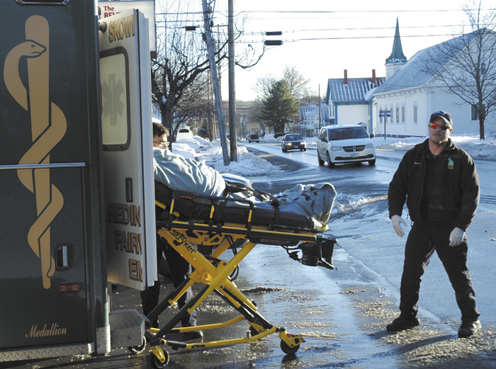 Abben Poyington, 24, of Skowhegan, is put into an ambulance with minor injuries Friday after he was struck by a vehicle while walking his bicycle in a parking lot on North Avenue in Skowhegan. An emergency worker stands by.