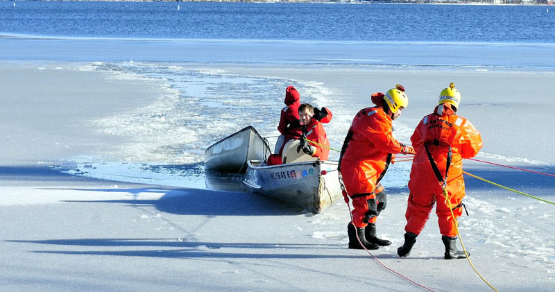 Area firefighters in survival suits drag a canoe to shore on North Pond in Mercer on Tuesday. Tracy Scott, 47, of Mercer, went out on the thin ice with the canoe to rescue a small dog and plunged into the water, but was later rescued.