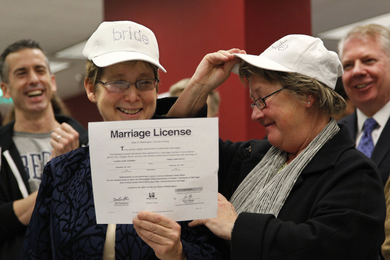 Claudia Gorbman, left, and partner Pam Keeley both wear caps reading “bride” as they display their marriage license Thursday in Seattle.