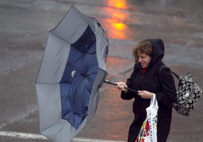 A woman reacts as a strong gust mangles her umbrella during a rain storm, Friday, Dec. 21, 2012, in Portland Maine. (AP Photo/Robert F. Bukaty)